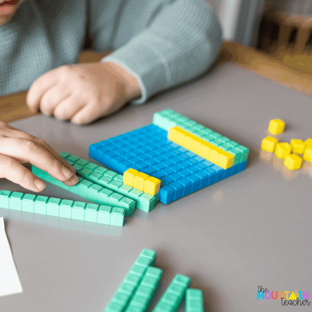 This photo shows a student building numbers using base ten blocks.